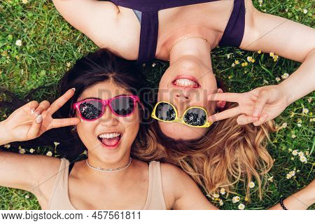 Top View Of Diverse Women In Trendy Sunglasses Gesturing V Sign And Looking At Camera With Smile Whi