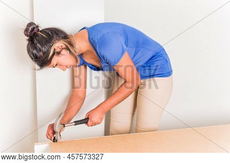 Latin Bolivian Strong And Independent Success Woman Assembly And Repair Furniture With Hammer.
