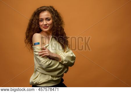 Portrait Of A Female Smiling After Getting A Vaccine. Woman Holding Down Her Shirt Sleeve And Showin
