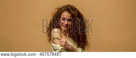 Portrait Of A Female Smiling After Getting A Vaccine. Woman Holding Down Her Shirt Sleeve And Showin