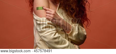 Close-up Of A Female After Getting A Vaccine. Woman Holding Down Her Shirt Sleeve And Showing Her Ar