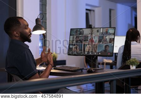 Male Employee Talking To Coworkers On Remote Videoconference Call, Using Online Teleconference Meeti