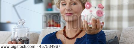 Portrait Of Senior Woman On Pension Weighing Containers With Saved Money For Future. Piggy Bank And 