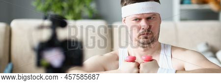 Portrait Of Strong Middle Aged Man Train On Camera Using Pink Dumbbells. Sportsman Filming Exercise 