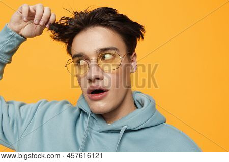 A Close Portrait Of A Funny Man Standing On An Orange Background In Bright Sunglasses Looking At The