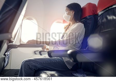 Young Woman Wearing Face Mask Is Using Smartphone Onboard, New Normal Travel After Covid-19 Pandemic