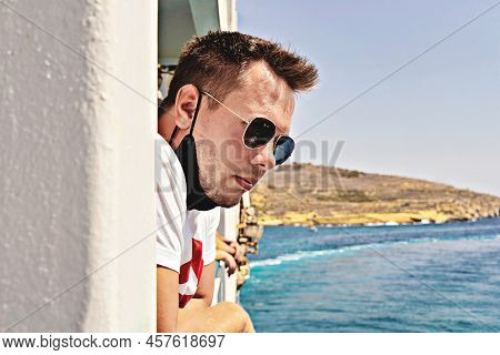 Attractive Guy In Sunglasses And Face Maskless Enjoys Of Fresh Sea Breeze On A Ferry In Mediterranea