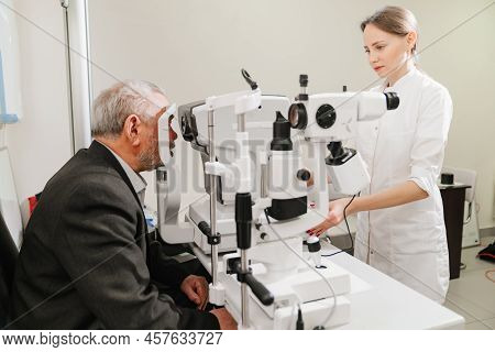 Doctor Examines Elderly Mans Eye On Screen Of Autorefractometer.