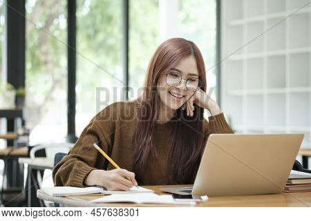 Young Collage Student Using Computer And Mobile Device Studying Online.