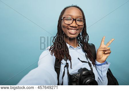 Positive Happy Photography Entusiast With Dslr Camera Making Peace Sign With Fingers While Taking Se