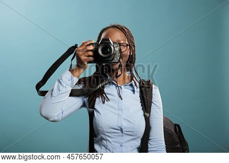 Confident And Creative Photographer Taking Pictures While Enjoying Leisure Time On Blue Background. 