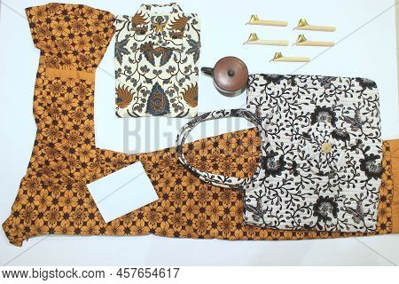 Flat Lay Batik Clotes With Canting, Small Pan And Wax Earthenware Glass Isolated On White Background