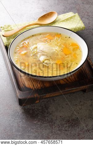 Light Chicken Soup With Pasta And Vegetables Close-up In A Bowl On A Wooden Tray On The Table. Verti