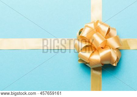Top View Of Gold Ribbon Rolled And Yellowbow Isolated On Colored Background. Flat Lay With Copy Spac