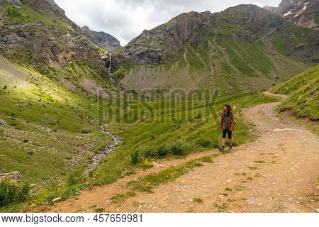 A Young Woman Next To The Salto De Tendenera Waterfall In The Ripera Valley, Panticosa, Pyrenees
