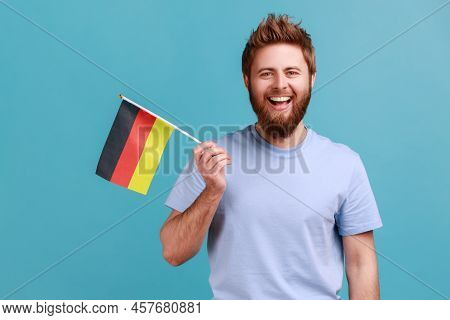 Portrait Of Delighted Satisfied Bearded Man Holding Germany Flag, Celebrating Day Of Germany - 3th O