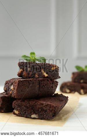 Delicious Chocolate Brownies With Nuts And Fresh Mint On White Table, Closeup