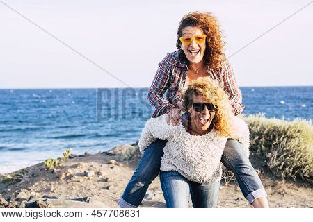 Happy And Cheerful Middle Age Couple Of Caucasian Women Enjoy And Play Together Carrying Eachother A