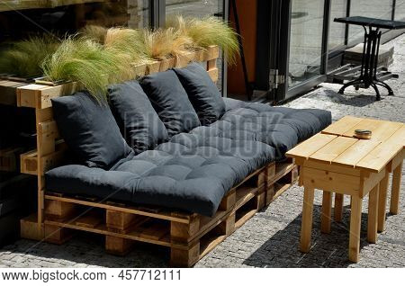 A Bench, A Sofa, On The Street, Made From Recycled Pallets And A Few Pillows, In Front Of A Store Or