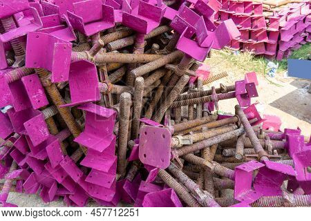 A Heap Of Support Material Steel Covering By Pink Rustproof Paint, On The Cocrete Floor In Front The