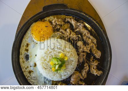 Breakfast With Rice, Fried Egg And Meat Or Beef With Garnish Corn And Leek Close Up Hot Plate Isolat