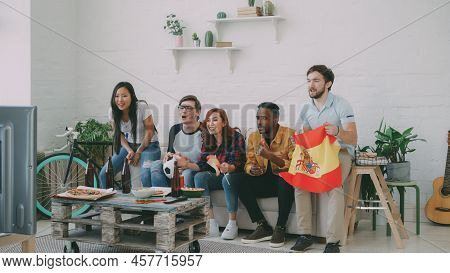 Multi-ethnic Group Of Friends Sports Fans With Spainsh Flags Watching Football Championship On Tv To