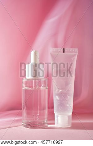 A Transparent Bottle Of Cosmetic Gel And A Bottle Of Serum On A Pink Background.