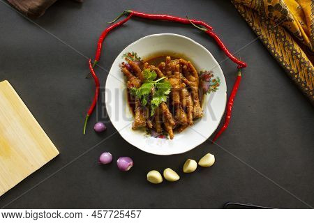Spicy Chicken Feet With Celery, Chili, Onion, Garlic Served With A White Plate Isolated From A Black