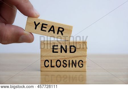 Hand Holding Wooden Blocks With Text - Year End Closing. Business And Financial Closing Concept