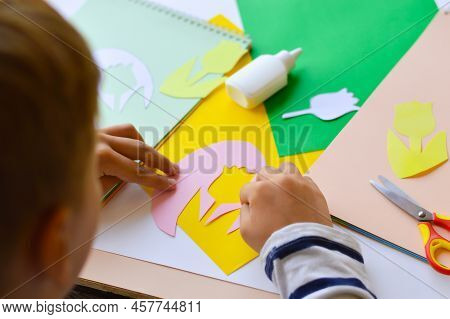 A Small Child Makes Paper Crafts For Mother's Day Or Birthday. A Boy Makes Paper Flowers For Mom. A 