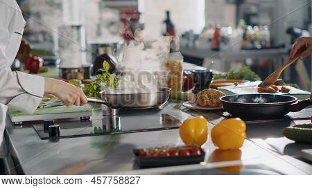 Professional Cook Preparing Gastronomy Dish In Frying Pan, Using Ingredients And Kitchen Utensils. A