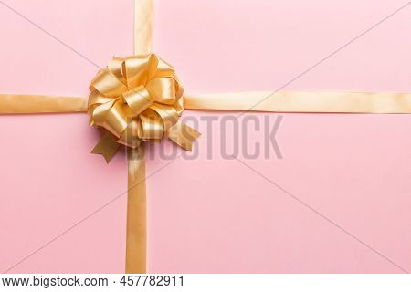 Top View Of Gold Ribbon Rolled And Yellowbow Isolated On Colored Background. Flat Lay With Copy Spac