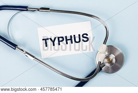 Stethoscope And White Card With Typhus Text On Blue Background. Medical Concept.