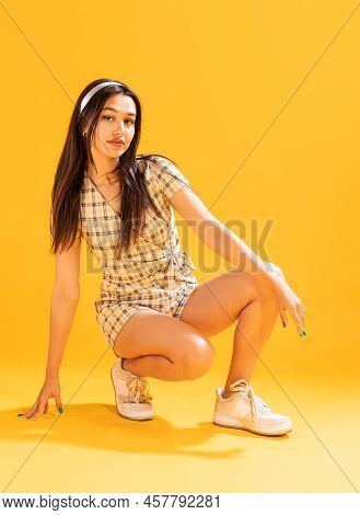 Portrait Of Beautiful Stylish Young Girl With Ribbon In Hair Posing Isolated Over Yellow Studio Back