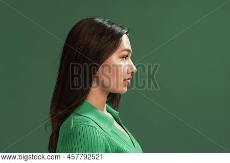 Portrait Of Beautiful Young Girl Posing Isolated Over Green Studio Background. Side View. Flyer