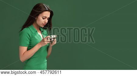 Portrait Of Concentrated Young Girl Looking At Photos In Retro Camera Isolated Over Green Studio Bac