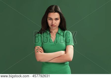Portrait Of Beautiful Young Girl Posing Isolated Over Green Studio Background. Offended Look