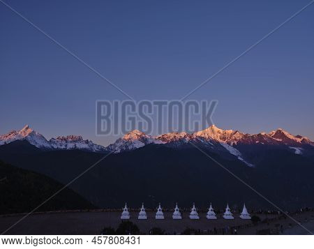White Pagodas Of Feilai Temple With Meili Snow Mountain At Sunrise In Background In China's Yunnan P