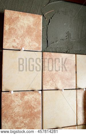 A Section Of Freshly Laid Brown And Cream Tiles On The Wall With Plastic Gaskets. Repair Work