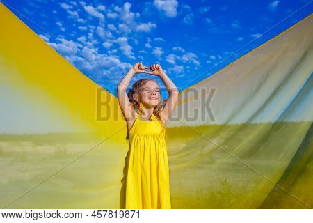 Ukrainian Girl 7 Years Old, She Is A Patriot Of Ukraine, Dressed In A Yellow Dress Against A Blue Sk