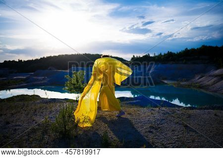 Happy Ukrainian Woman Running In Nature. In A Long Yellow Dress. Symbol Of Freedom Of Ukraine. Woman