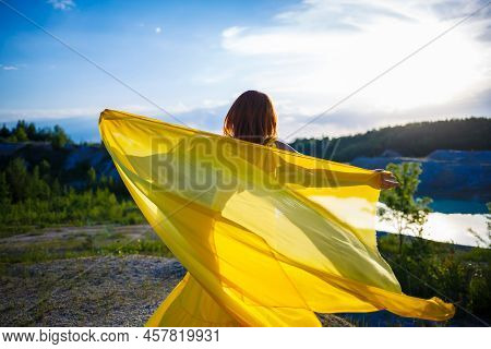 Happy Ukrainian Woman Running In Nature. In A Long Yellow Dress. Symbol Of Freedom Of Ukraine. Woman