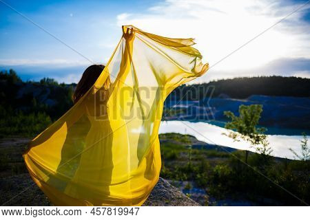 Happy Ukrainian Woman Running In Nature. In A Long Yellow Dress. Symbol Of Freedom Of Ukraine. Woman