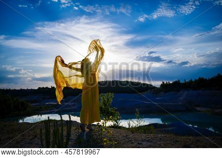 Happy Ukrainian Woman Running In Nature. In A Long Yellow Dress. Symbol Of Freedom Of Ukraine. Woman