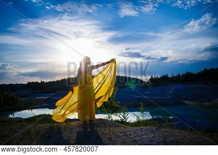 Happy Ukrainian Woman Running In Nature. In A Long Yellow Dress. Symbol Of Freedom Of Ukraine. Woman