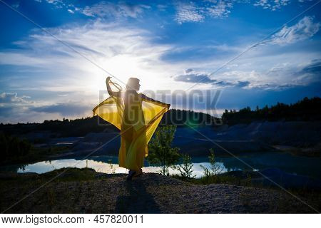 Happy Ukrainian Woman Running In Nature. In A Long Yellow Dress. Symbol Of Freedom Of Ukraine. Woman