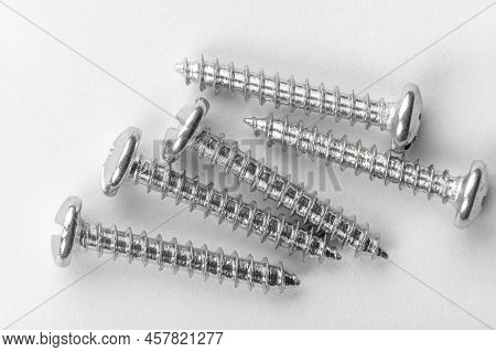 Five Screws On White Paper. Detailed Macro Photo. Self Tapping Screws. Set Of Screw