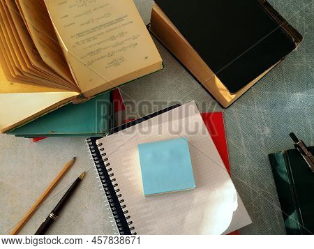 Notebooks And Paper For Notes Are Stacked. Books, Pen, Pencil, And Compass Are Arranged Around Them 