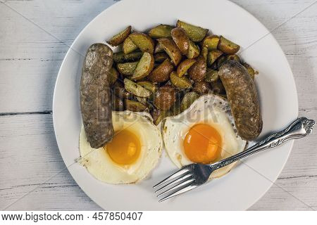 Two Fried Eggs Served With Italian Sausage And Homefries