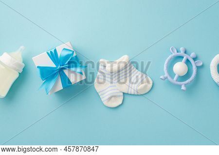 Baby Boy Concept. Top View Photo Of Giftbox Teether Milk Bottle And Tiny Socks On Isolated Pastel Bl